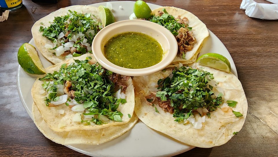 Tacos and queso served on bright dishes